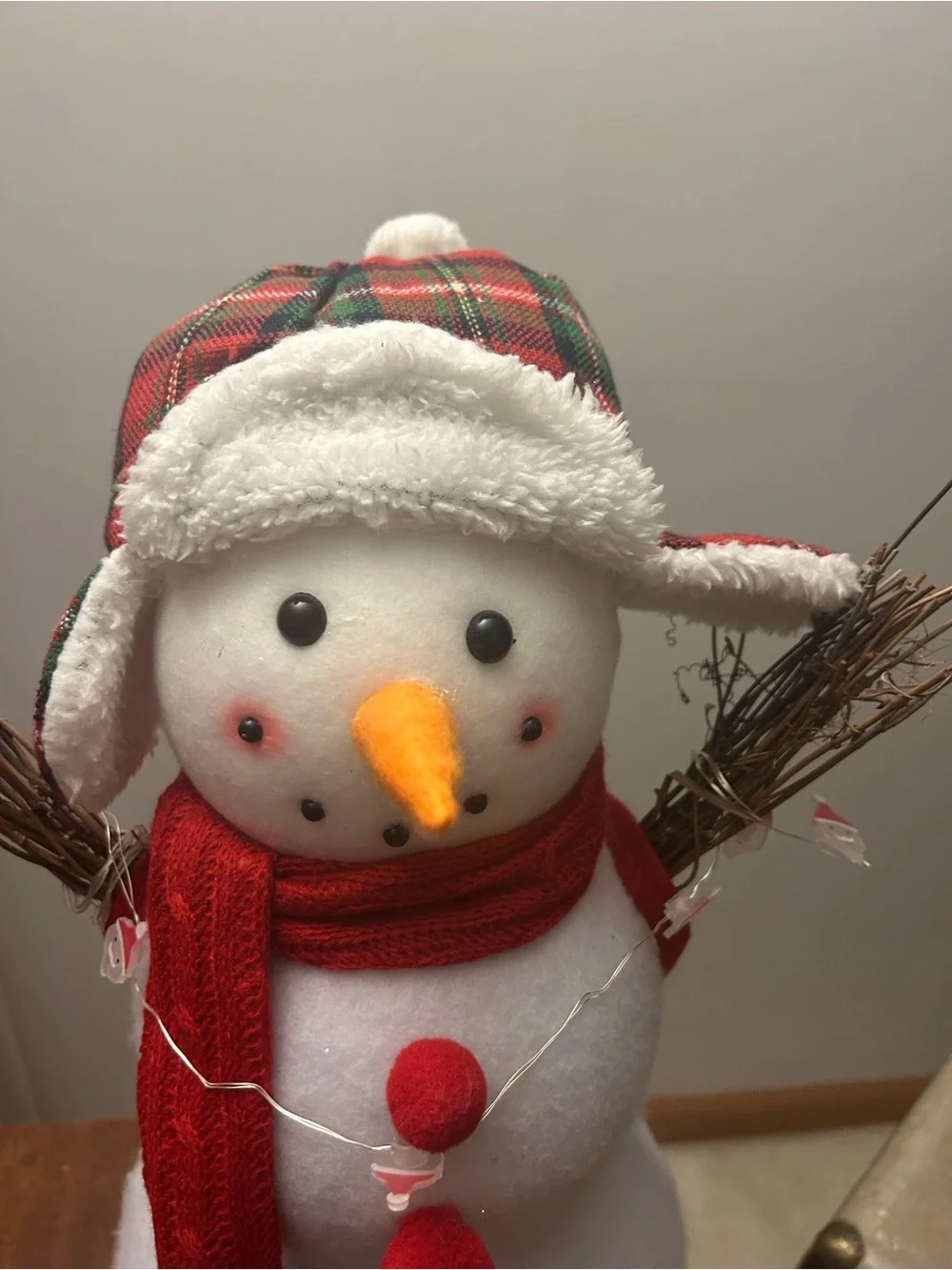 Snowman decoration with twig arms, plaid hat and Santa accent lights New